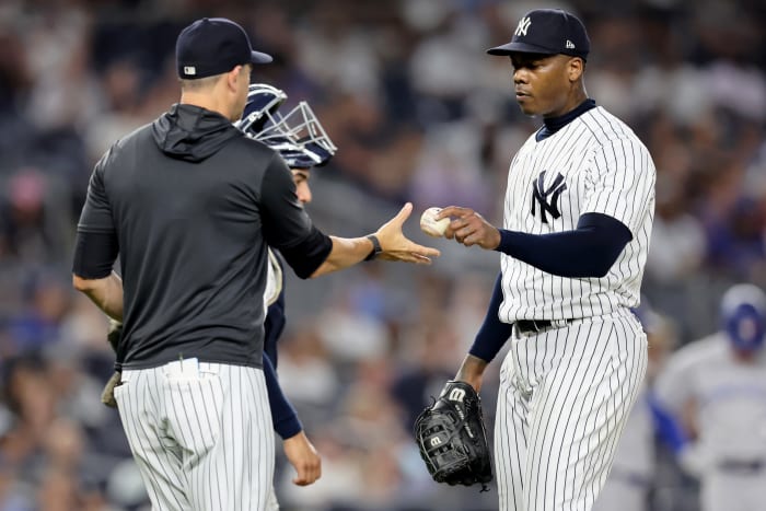 Aug 19, 2022; Bronx, New York, USA; New York Yankees relief pitcher Aroldis Chapman (54) hands the ball to manager Aaron Boone (17) after being taken out of the game against the Toronto Blue Jays during the ninth inning at Yankee Stadium.
